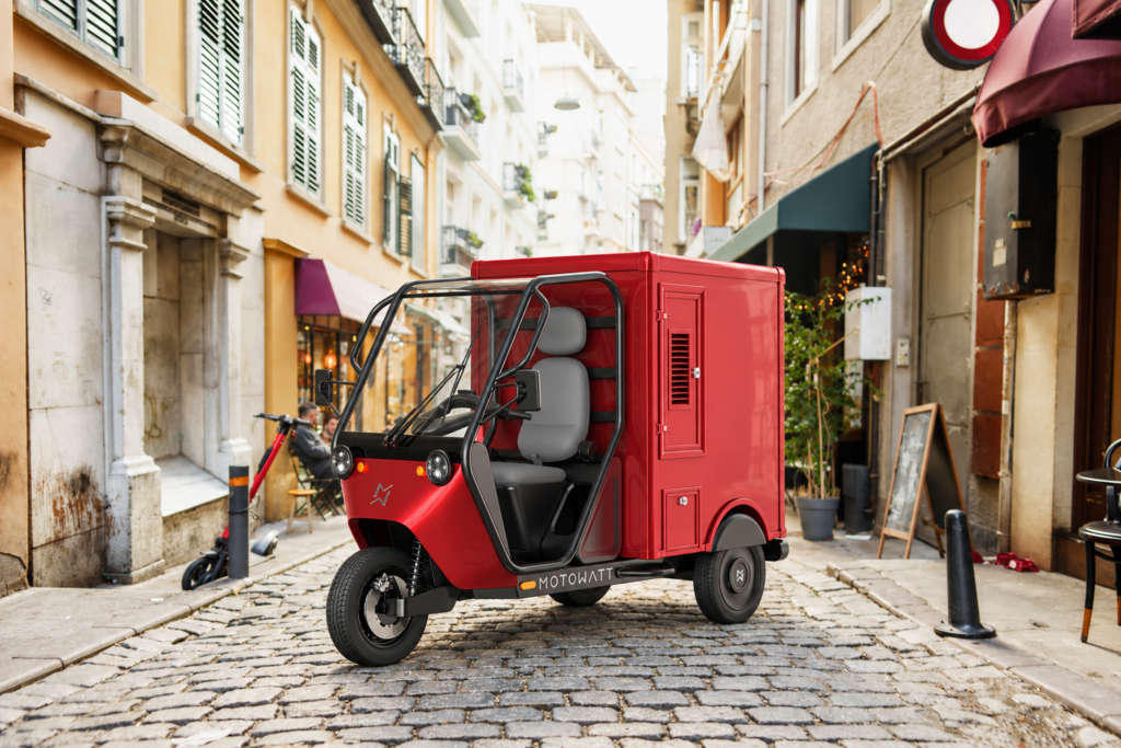 Triporteur magasin Motowatt rouge dans une rue pavée
